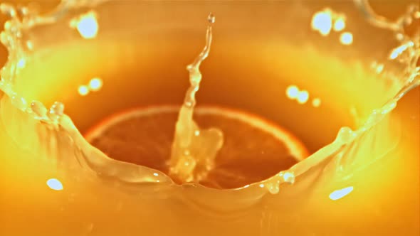 A Piece of Fresh Orange Falls Into the Orange Juice with Splashes