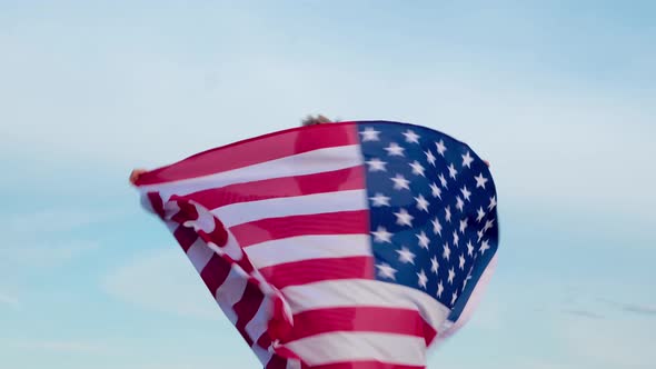 Happy Little Boy Spinning with USA Flag Outdoors Over Blue Sky at Summer Waving American Flag