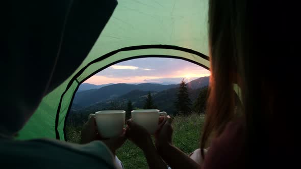 Young Couple Sitting in a Tourist Camping Tent with a Cup of Hot Tea