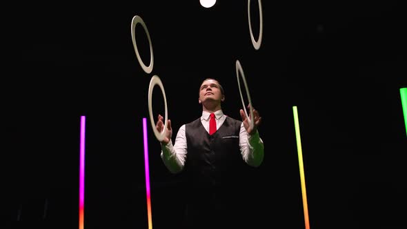 Camera Rotates Around Professional Male Juggler Juggling White Rings