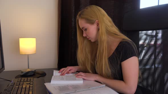 A Young Beautiful Woman Sits at a Desk in Front of a Computer and Studies - Closeup