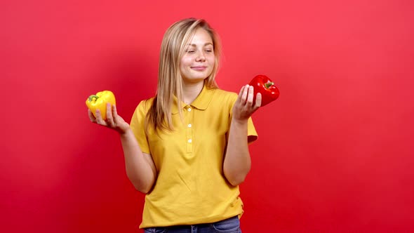 Cute and Slightly Fat Girl in a Yellow T-shirt Holding a Yellow and Red Pepper in Her Hand.