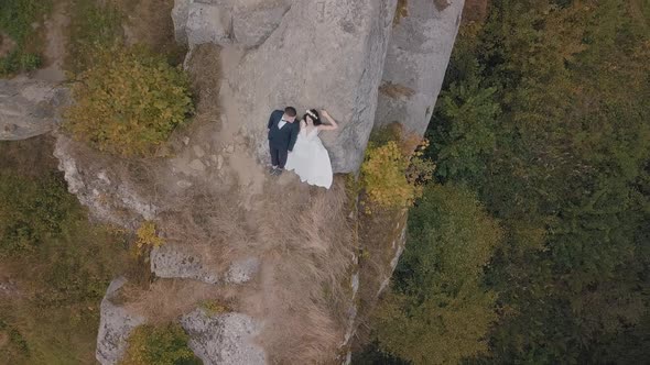 Newlyweds Stand on a High Slope of the Mountain. Groom and Bride. Aerial View