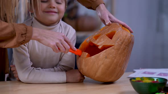 Mom Shows Her Son How to Make a Halloween Jack Lantern Face on the Big Orange Pumpkin