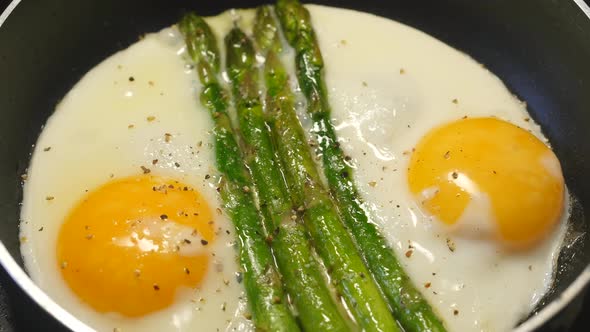 Preparing Fried Eggs with Fresh Asparagus on Frying Pan