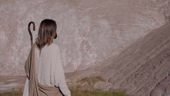 Jesus Christ with a Staff in Robe is Standing on the Mountain and Looking Far