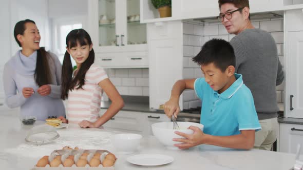 Happy asian parents in kitchen with son and daughter, baking together