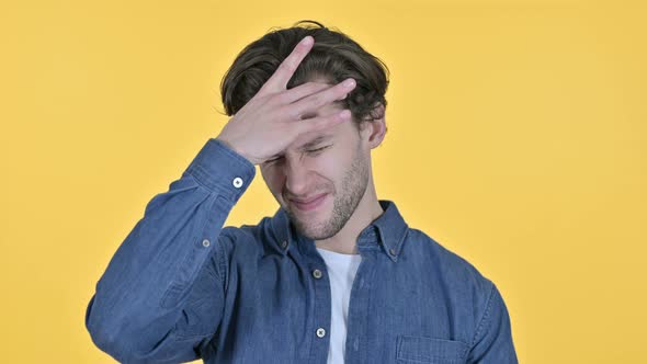 Young Man Having Headache, Pain in Head on Yellow Background