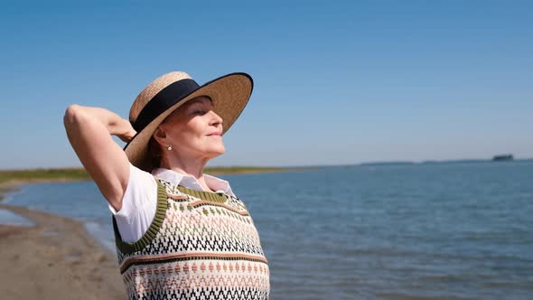 Portrait of an Elderly Woman in a Hat Near the Sea or Ocean She Enjoys the Fresh Air in Nature