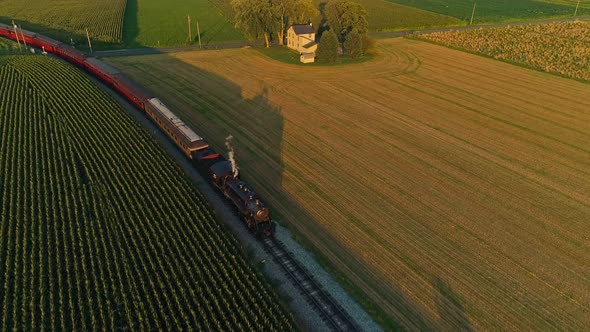 Aerial Frontal View of A Steam Passenger Train Passing Thru Corn Fields and Farmlands During the Gol