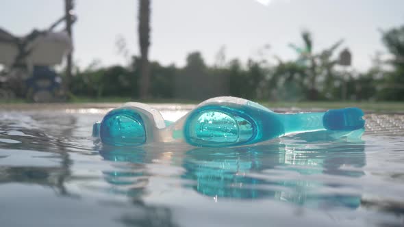 A Closeup of Blue Goggles on an Open Pool Surface on a Sunny Day