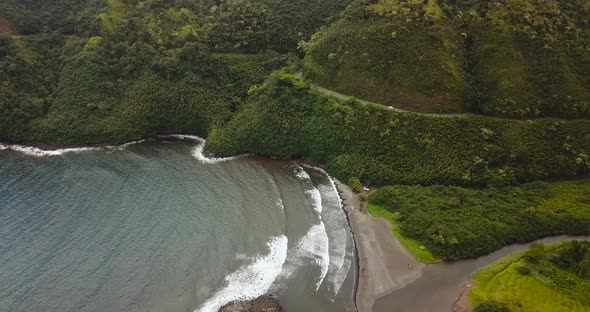 An aerial shot of the road to Hana in Maui. Showcasing the blue coast line beside the lush forestry