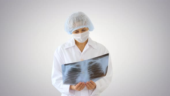 Female Doctor Wearing Medical Mask Looking at X-ray Image on Gradient Background