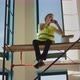 A Worker Eats a Sandwich on the Construction Site Sits High on Scaffolding - VideoHive Item for Sale