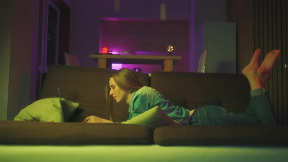 A Woman is Using Laptop for Online Shopping or Typing Message on a Sofa at Home