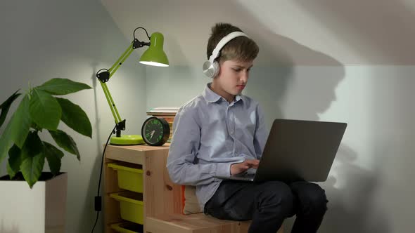 Boy Of Ten Sitting In The Nursery With Laptop On His Lap