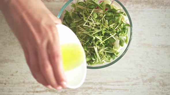 Dressing A Fresh Salad Of Vegetables And Fresh Microgreens