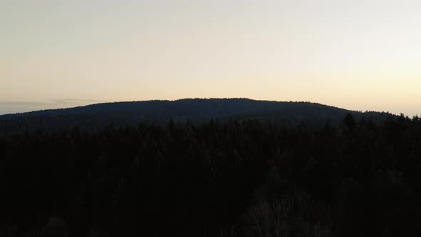 Aerial clip over a hill in the Bavarian alps area, during sunrise. Strong sun backlight.