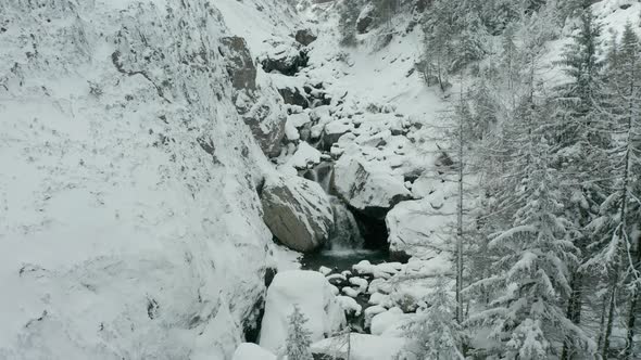 Flying away from small waterfalls in snow covered wilderness