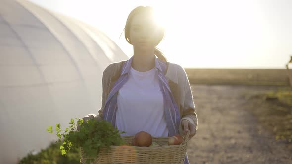 Happy Farmer Showing Basket with Fresh Harvested Vegetables and Smiling in Camera on Countryside