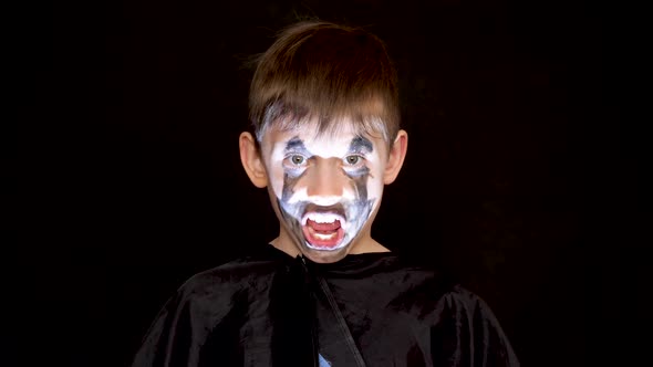 Portrait of a caucasian boy 7-8 years old in a carnival costume with makeup on the face of an evil z