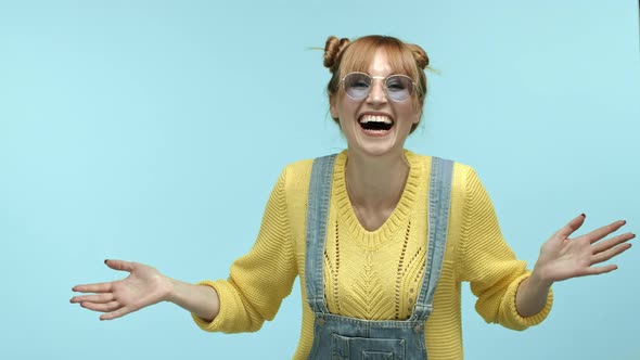 Slow Motion of Funny and Cute Young Woman in Sunglasses and Sweater Raising Hands and Looking Happy