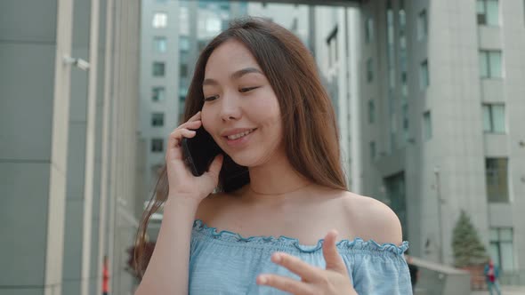 Young Asian Woman in City Standing Talking on Cell Phone