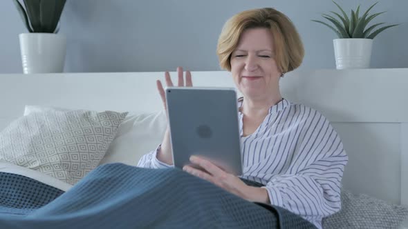 Online Video Chat on Tablet By Tired Old Senior Woman in Bed