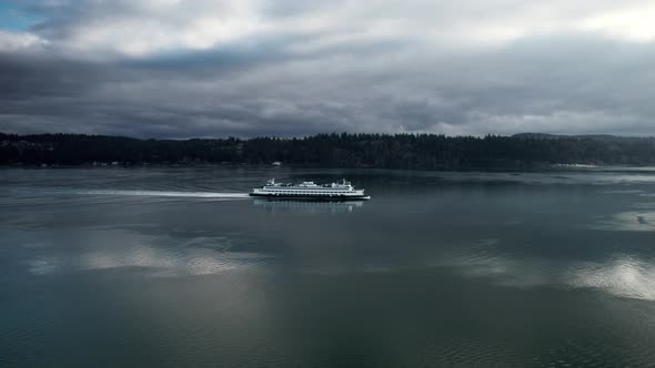 Slowly tracking a commuter ferry as it cruises along a calm waterway reflecting dark gloomy clouds,