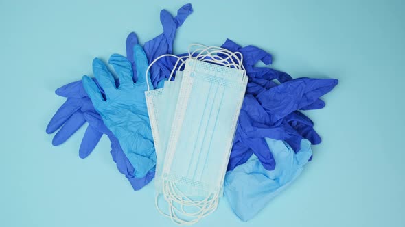 pile of disposable medical blue gloves and a stack of masks