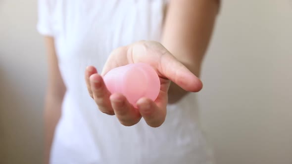 Woman Hand Holding Pink Menstrual Cup Isolated on White Background