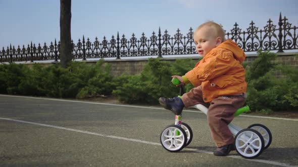 Funny Toddler Getting Off Bike in Slow Motion. Happy Kid Looking on Sky.