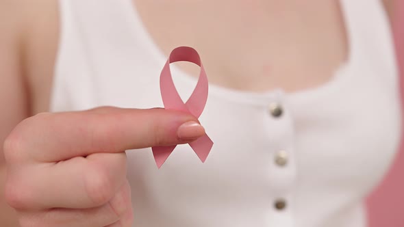 Close Up, Woman Holding Symbolic Pink Ribbon, Brest Cancer Awareness and Hope Concept