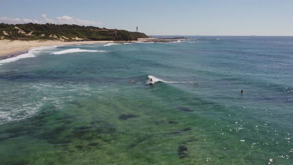 aerial tracking shot of a longboard surfer at pebbly beach