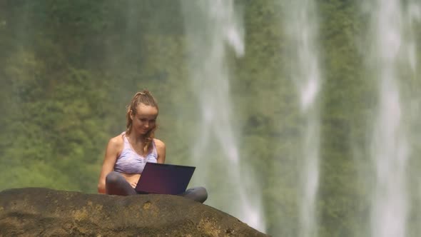 Wind Shakes Hair Girl Works on Notebook By Waterfall