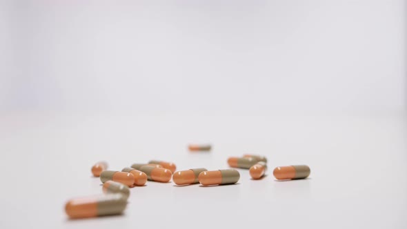 Medical capsules falling on white background in slow motion.