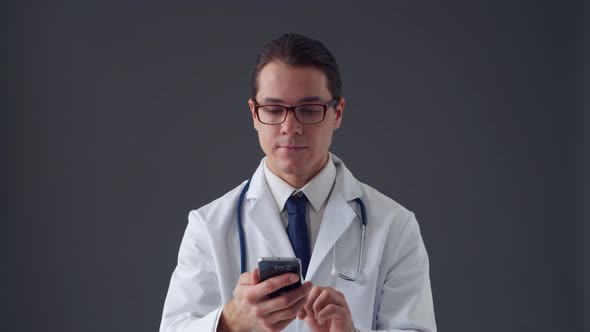 Studio portrait of young professional medical doctor standing over grey background