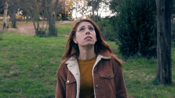 Desperate lonely young woman looking up in the park.Desperation,help,pray