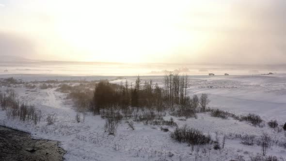 Snow Falling Over Wintry Landscape With Cars Passing By On Distant Road At Sunset. wide aerial