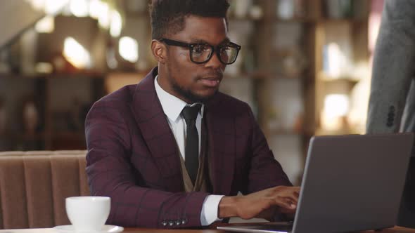 Afro-American Businessman Working on Laptop in Cafe