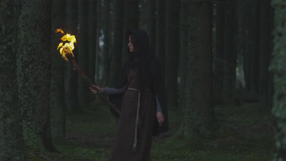 Woman with fire torch in the woods