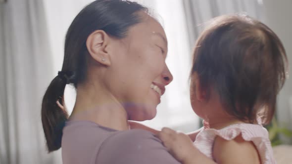 Affectionate Asian Mom Cuddling Baby Girl