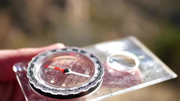 Close up on a compass in the hands of a lost hiker being used in an emergency survival situation to