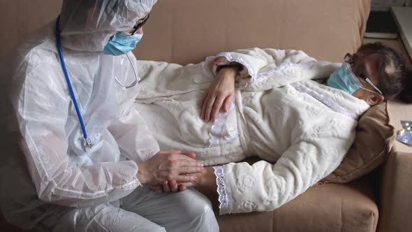 Doctor in a Protective Suit Helping Senior Old Woman Patient at Checkup Medical Consultation at Home