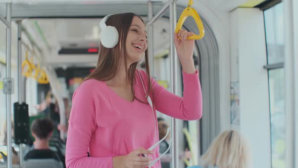 Young Woman Holding Handle While Moving in the Modern Tram. Happy Passenger Enjoying Trip at the