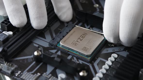 A technical specialist's hand in white gloves removing the CPU from socket on the motherboard