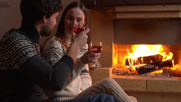 Young Romantic Couple Sitting in Front of Fireplace at Home Drinking Red Wine