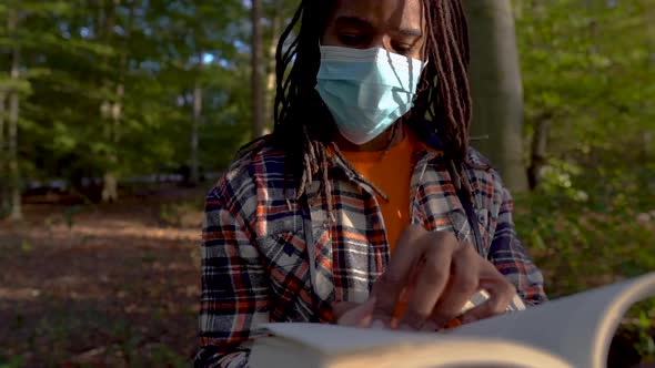 African American Man Reading Outside While Wearing Face Mask, Social Distancing