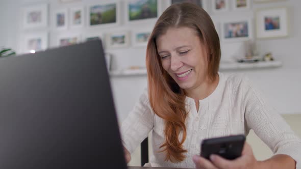 Beautiful Adult Woman With Red Hair Works Laptop At Home