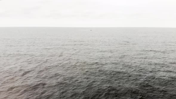 Aerial shot of one lone motor boat speeding through the endless waves of the open ocean.